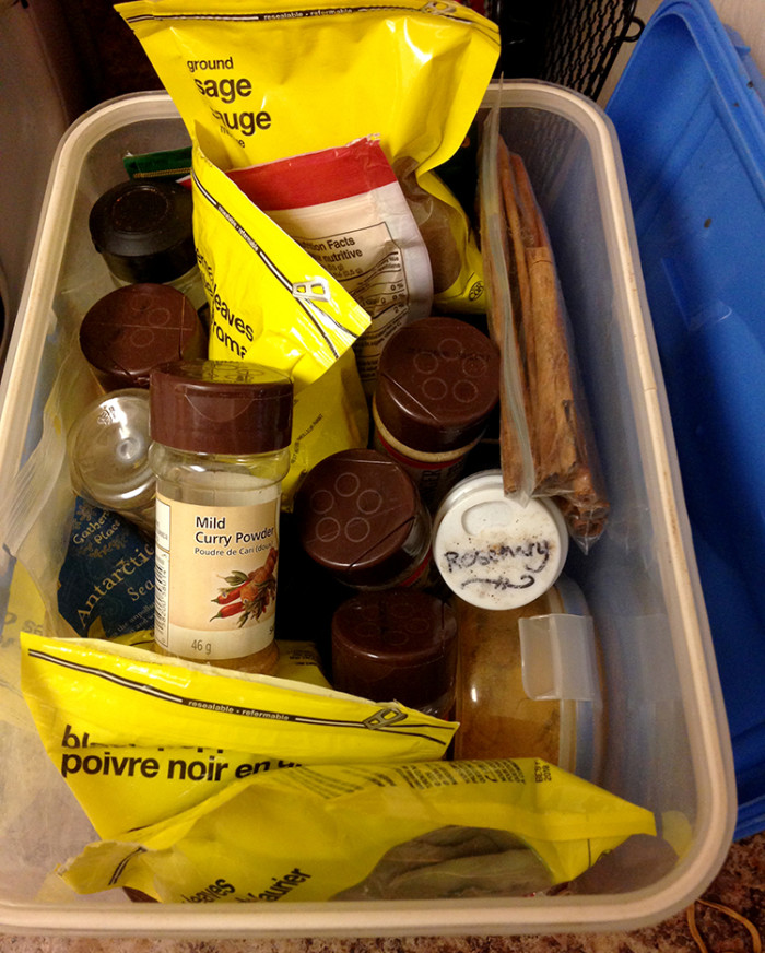 Tupperware box overflowing with spices in bags and bottles